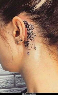 a woman's ear with a flower tattoo on her left side behind the ear