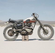 an old dirt bike is parked in the middle of the desert with no one around it