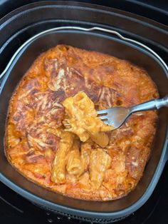 a fork in a dish with meat and cheese