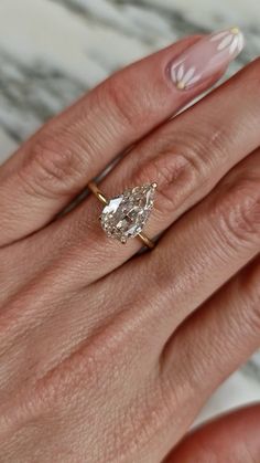 a woman's hand with a ring on it and a diamond in the middle