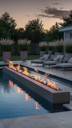 a fire pit in the middle of a pool with lounge chairs around it at sunset