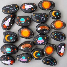 painted rocks are arranged in the shape of rockets and planets, with stars on them