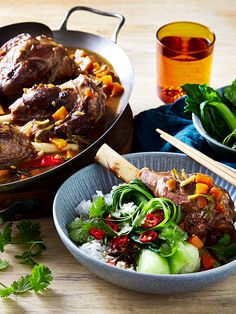 two bowls filled with meat and vegetables on top of a wooden table next to chopsticks