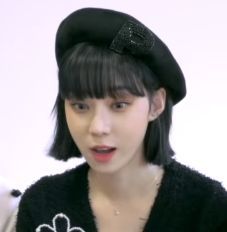 a young woman wearing a black hat and sweater with an embellished flower on it