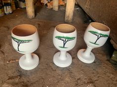 three white egg cups with trees painted on them