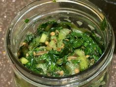 a glass jar filled with green vegetables and nuts