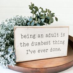 a wooden sign that says being an adult is the dumbest thing i've ever done