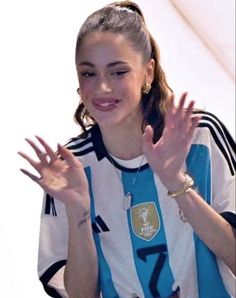 a woman with her hands in the air while wearing a blue and white striped shirt