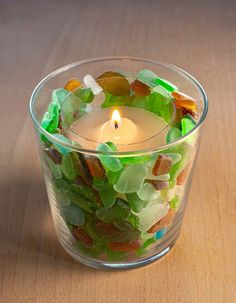 a glass bowl filled with gummy bears and a lit candle on top of a wooden table