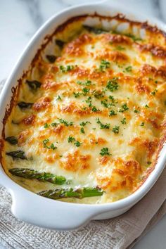 a casserole dish with asparagus and cheese in it on a white towel