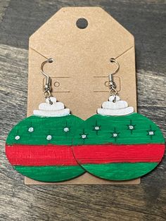 wooden earrings with green and red christmas ornaments on the front, sitting on a table