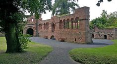 an old brick building sitting next to a lush green park filled with lots of trees