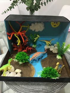 an open box filled with different types of toy animals and plants on top of a table