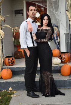 a man standing next to a woman in front of a house decorated with pumpkins