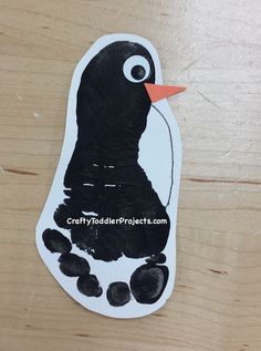 a penguin made out of black paper on a wooden table