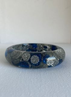 Was £35 now £27 This vintage chunky bangle is the cats meow.  With sparkly blue and silver accents that really catch the light.  This bangle can make any outfit a bit more festive.  And for me the more the merry for bangles so stack them, even have a look of you would like at all my other bangles. The condition is good for its age but the plastic is a bit cloudy to what it may had been and it does have light scratches and scuffs. Measurements: to come All sales are final so please ask any and all questions prior to purchasing. I always combine shipping at no extra cost so message me before hand and I will adjust the shipping price to show combined shipping prices.  I refund  any and all Postal overcharges if there are any. If there is something you are looking for that I do not have, feel Silver Glitter Bracelet As Gift, Silver Glitter Bracelets As A Gift, Silver Glitter Bracelets As Gifts, Blue Glitter Jewelry For Party, Festival Accessories, Holiday Jewelry, Silver Bangle, Cats Meow, Silver Accents