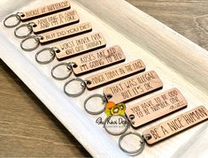 six keychains with different sayings on them sitting in a white tray next to each other