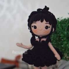 a crocheted doll is standing next to a potted plant