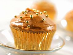 a cupcake with chocolate frosting and gold sprinkles on a plate