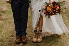 a bride and groom holding hands walking through the grass with flowers in their bouquets