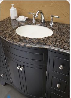 a bathroom vanity with granite counter top and two faucets on the sink area