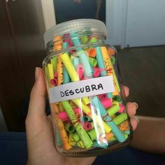 a person holding a jar filled with colorful crayons and writing on the label