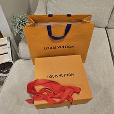 two louis vuitton bags sitting on top of a couch next to each other