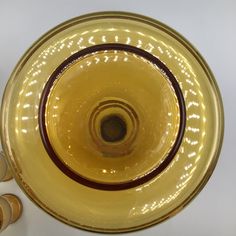 a yellow glass bowl sitting on top of a white table next to some glasses and spoons