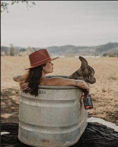 a woman in a hat is sitting in a barrel with a cat on her lap