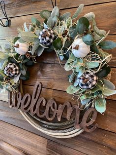 a welcome wreath hanging on the side of a wooden wall