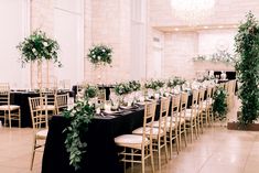 the tables are set with black linens, greenery and candles for an elegant wedding reception