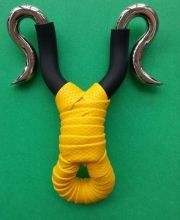 a yellow and black piece of art on a green surface with two metal hooks hanging from it's sides