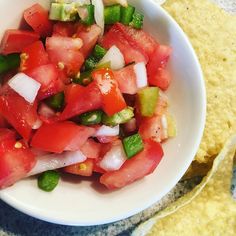 a white bowl filled with lots of veggies next to tortilla chips