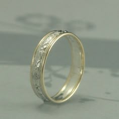 a wedding ring with an intricate design on the inside and outside, sitting on a table