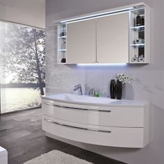 a bathroom with a sink, mirror and lights on the wall above it's cabinets