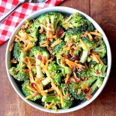 a bowl filled with broccoli and cheese on top of a wooden table