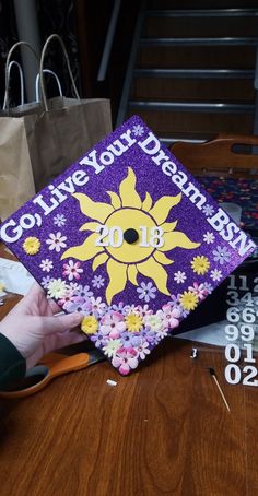 a purple and yellow graduation cap sitting on top of a wooden table