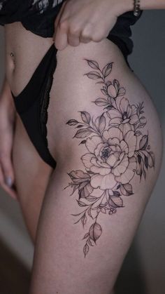 a close up of a person's thigh with flowers tattooed on the side and behind her