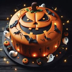 a cake decorated with pumpkins and bats on a wooden table surrounded by halloween lights