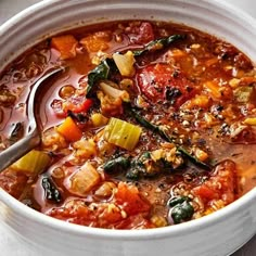 a white bowl filled with vegetable soup on top of a table