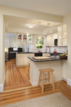 a kitchen with white cabinets and black counter tops, hardwood floors, and an area rug on the floor