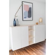 a white cabinet with shelves and vases on top of it in a living room