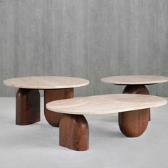 two wooden tables sitting next to each other on top of a cement floor with concrete walls in the background