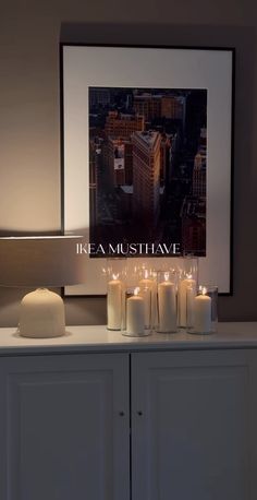 there are many lit candles on top of the cabinet in front of the picture that says headmusshave