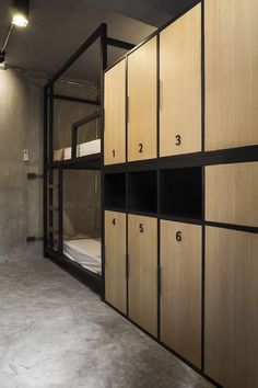 an empty room with bunk beds and wooden cupboards on the wall, in front of a concrete floor