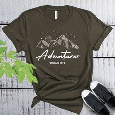 This Adventurer Wild And Free t-shirt is everything you've dreamed of and more. It feels soft and lightweight, with the right amount of stretch. It's comfortable and flattering for both men and women. Adventure Shirt, Wild And Free Shirt, Camp life shirt, hiking gift shirt * 100% combed and ring-spun cotton  * Heather colors contain polyester * Fabric weight: 4.2 oz (142 g/m2) * Pre-shrunk fabric * Side-seamed construction * Shoulder-to-shoulder taping * Unisex Size Relaxed Fit Graphic Print Top For Adventure, Graphic Tee With Text Print For Adventure, Adventure Graphic Print Crew Neck Top, Relaxed Fit Text Print Top For Outdoor Activities, Outdoor Slogan Crew Neck Top, Outdoor Slogan Tops With Crew Neck, Graphic Tee With Text Print For Outdoor Activities, Graphic Tee Tops With Text Print For Outdoor Activities, Pre-shrunk Relaxed Fit Adventure Shirt