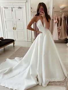 a woman taking a selfie in front of a mirror wearing a white wedding dress