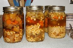 four jars filled with food sitting on top of a counter next to utensils