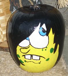 a painted pumpkin sitting on the ground next to a basket