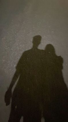 two people standing next to each other with their shadows on the ground in front of them